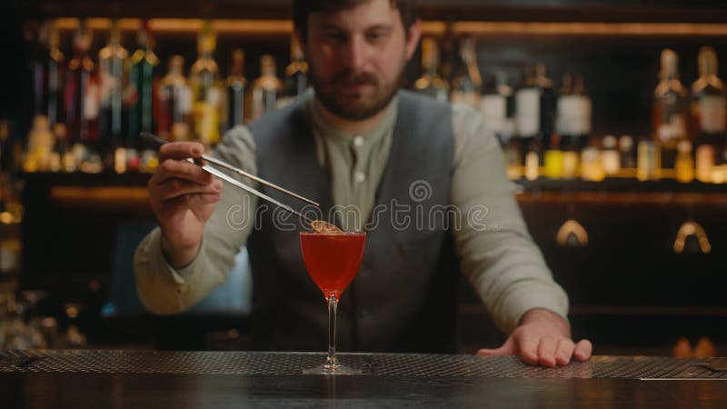 Barmann schmückt alkoholische Getränke in Cocktailglas an der Bar