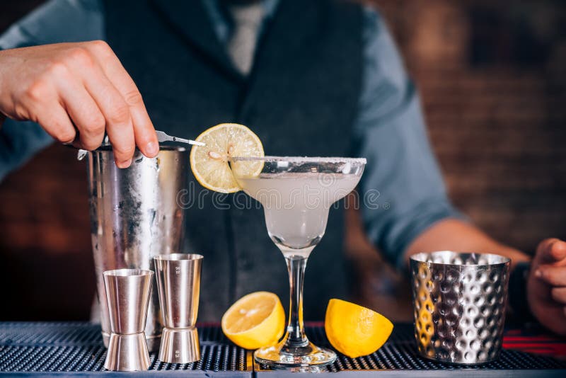 Barmanu garnirowania napój, dolewania wapna margarita w galanteryjnym szkle przy restauracją zdjęcie stock Barmanu garnirowania napój, dolewania wapna margarita w galanteryjnym szkle przy restauracją zdjęcie stock