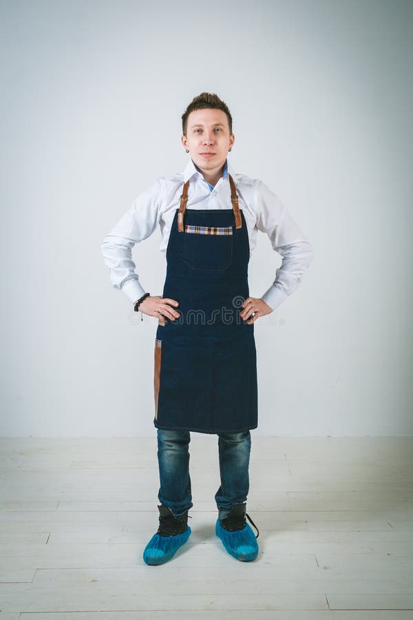 A shoot of young caucasian man in apron as a barmen with arms akimbo Isolated against white background.