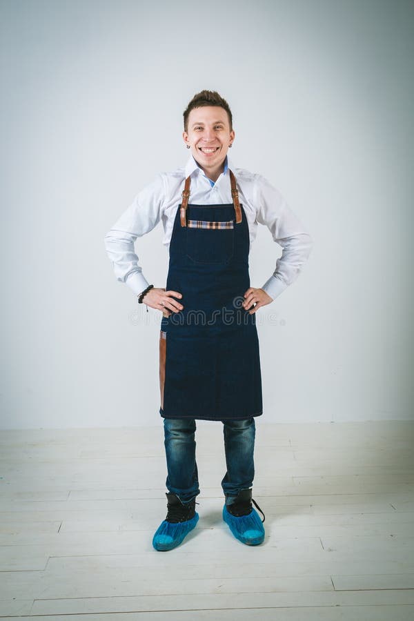 A shoot of young caucasian man in apron as a barmen with arms akimbo Isolated against white background.