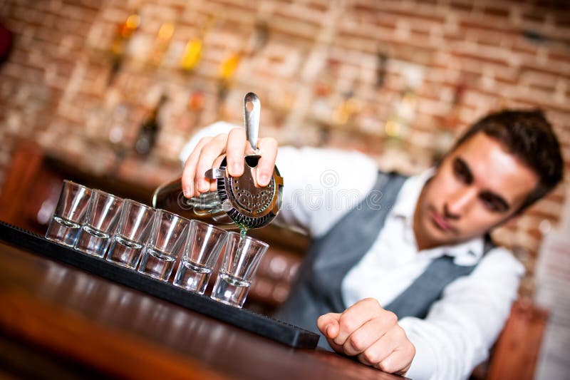 Barmixer, Der Alkoholisches Getränk In Kleine Gläser Auf Bar Gießt