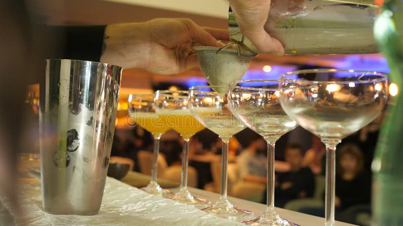 Barmixer, der frischen Orangensaft in ein Glas bei der Herstellung eines alkoholischen Cocktails gießt lizenzfreies stockfoto Barmixer, der frischen Orangensaft in ein Glas bei der Herstellung eines alkoholischen Cocktails gießt lizenzfreies stockfoto