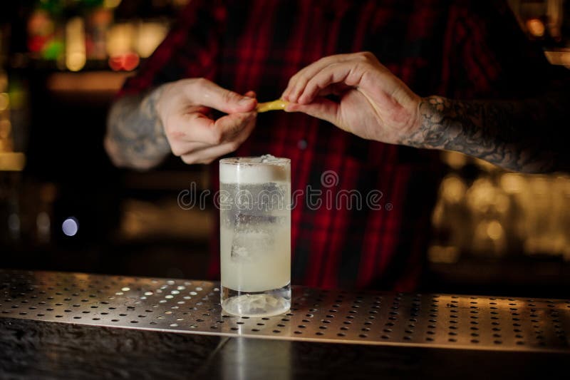 Barmixer, der Saft des orange Eifers einem Gin Fizz-Cocktail hinzufügt lizenzfreie stockbilder Barmixer, der Saft des orange Eifers einem Gin Fizz-Cocktail hinzufügt lizenzfreie stockbilder
