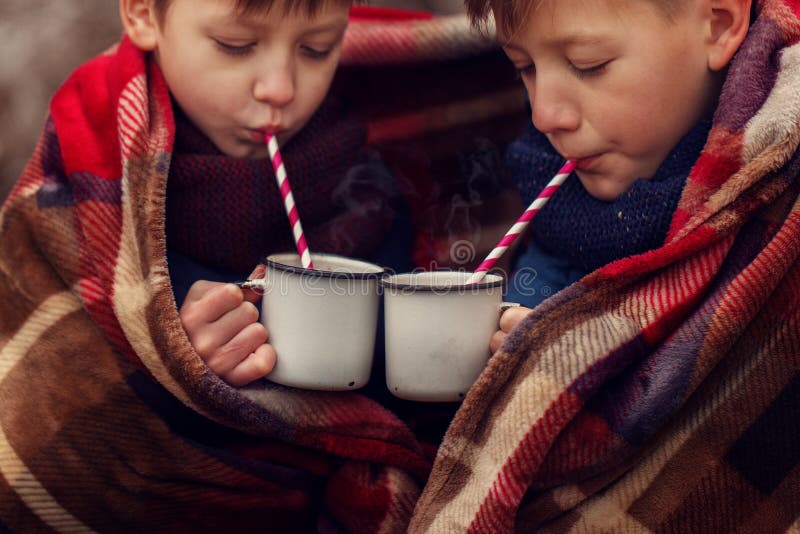 Barn dricker varm choklad under den varma filten i vinterskogjul semestrar royaltyfri foto Barn dricker varm choklad under den varma filten i vinterskogjul semestrar royaltyfri foto