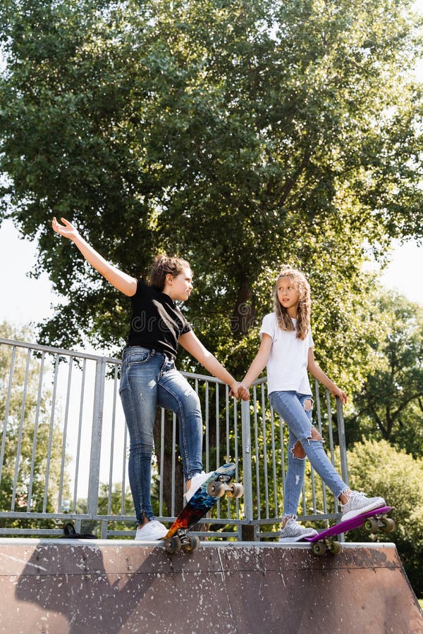 Barn flickor som kissar tillsammans. vänskap. kompisar redo att åka på penny-bord på lekplats för skateboard-parkering. sport royaltyfria bilder