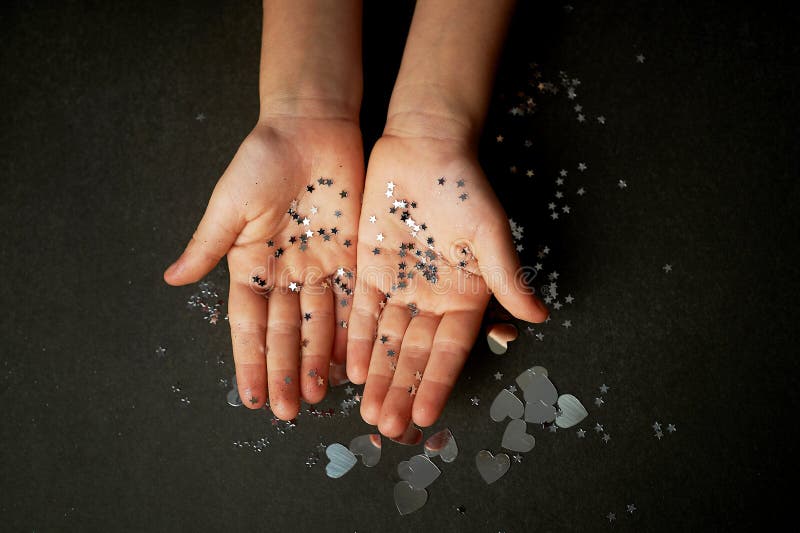 Children`s hands in glitter sours of silver color. Faith in miracles. Children`s hands in glitter sours of silver color. Faith in miracles.