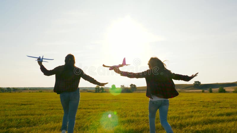 Barn i solljus med ett flygplan i handen. drömmar om flygning. begreppet lyckad barndom. två flickor leker med