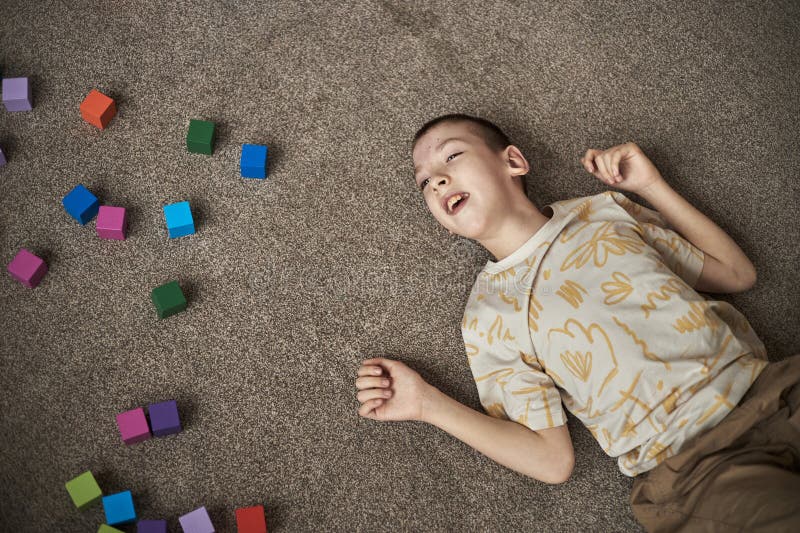 Barn med funktionsnedsättning som leker med att matta spelar med färgstarka block arkivbilder