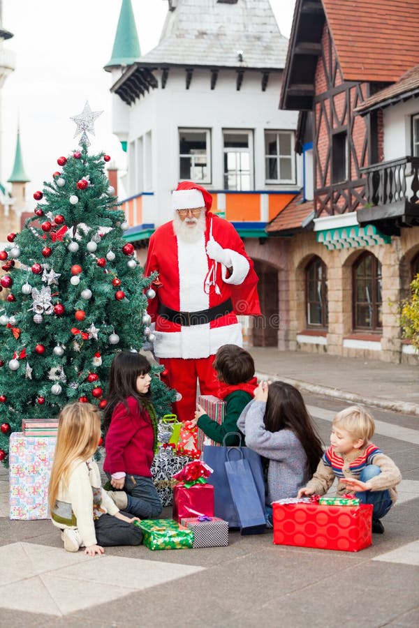Barn med gåvor som ser Santa Claus royaltyfria bilder Barn med gåvor som ser Santa Claus royaltyfria bilder