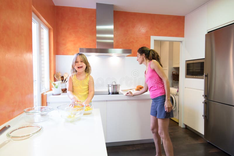 Barn med rå potatisar som ser le bredvid moder i kitche arkivfoton Barn med rå potatisar som ser le bredvid moder i kitche arkivfoton