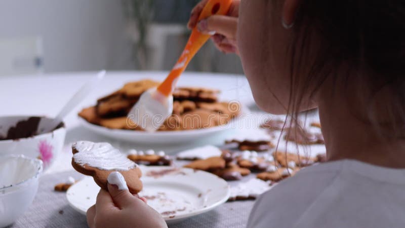 Barn som dekorerar gingerbröd med vitt glas