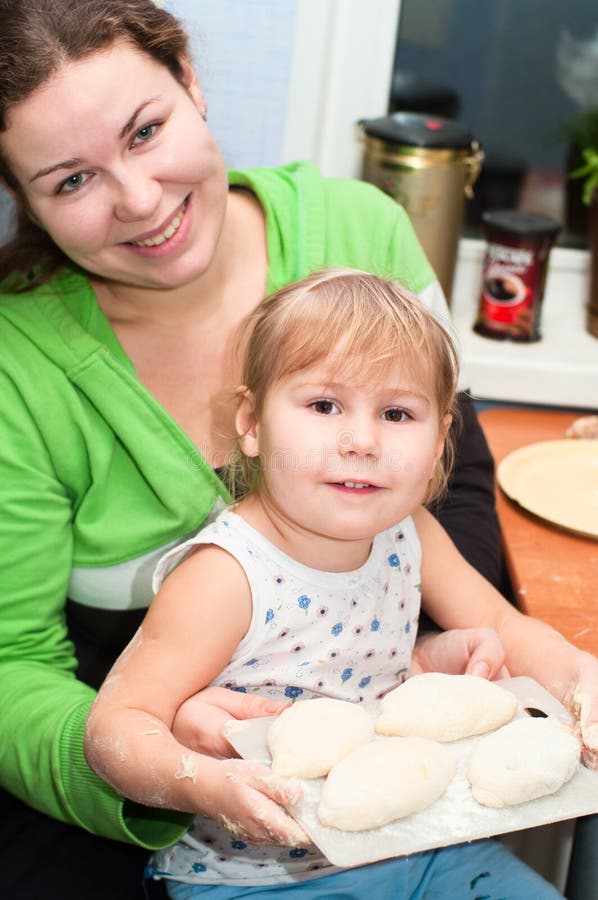 Mother and little child cooking at kitchen. Making pies. Mother and little child cooking at kitchen. Making pies