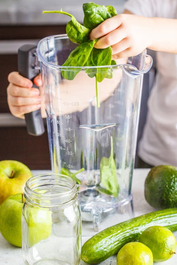 Barn som lagar mat smoothien för spenatäpplegurka Baserat matbegrepp för sund växt royaltyfri bild Barn som lagar mat smoothien för spenatäpplegurka Baserat matbegrepp för sund växt royaltyfri bild
