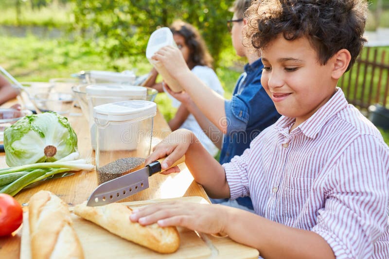 Barn som styckar baguette-bröd i matlagningsklass fotografering för bildbyråer
