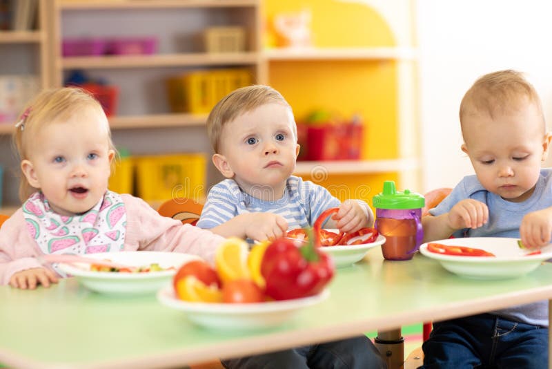 Children toddlers eating healthy food in nursery or kindergarten. Children toddlers eating healthy food in nursery or kindergarten