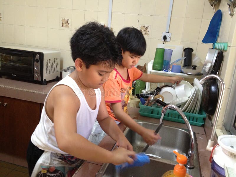Asian children washing the dishes for Child labour vs Household Chores concept. Asian children washing the dishes for Child labour vs Household Chores concept.