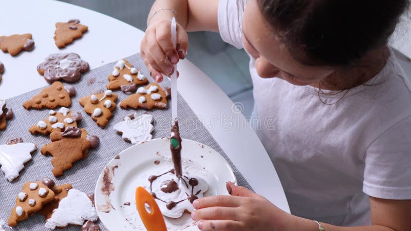 Barnet använder chokladgaze på xmas-kakor