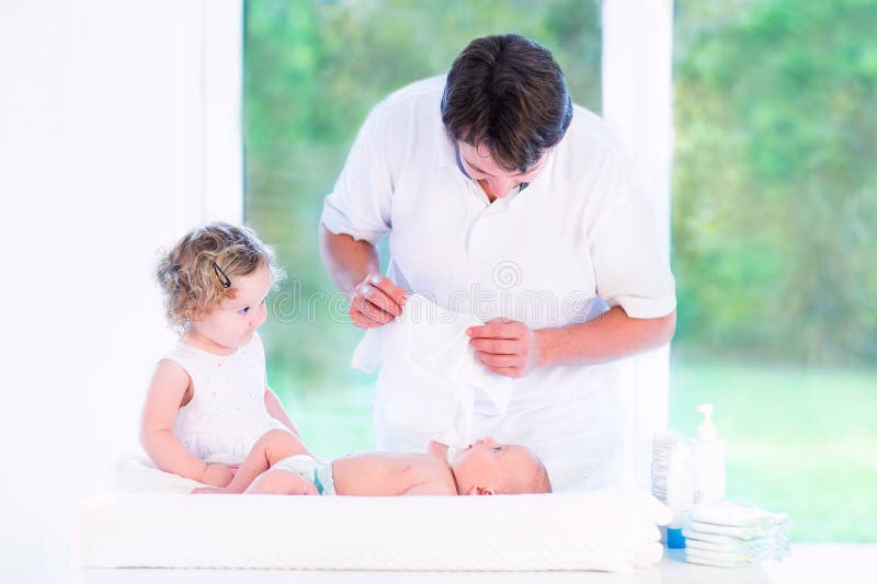 Barnet avlar att klä hans nyfödda son och daugher arkivfoto Barnet avlar att klä hans nyfödda son och daugher arkivfoto