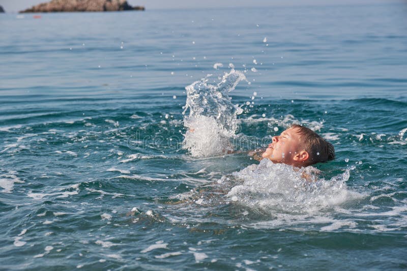 Barnet drunknar i havet och skriker och viker armarna.. royaltyfri bild