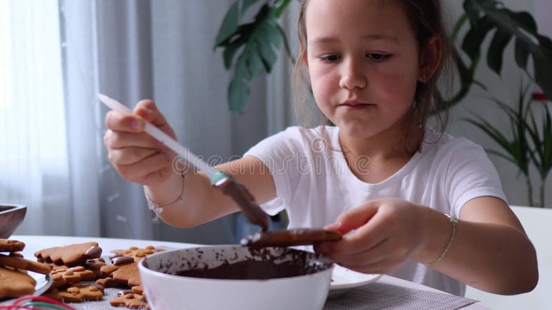 Barnet håller ett gingerbröd i handen och målar det med pensel