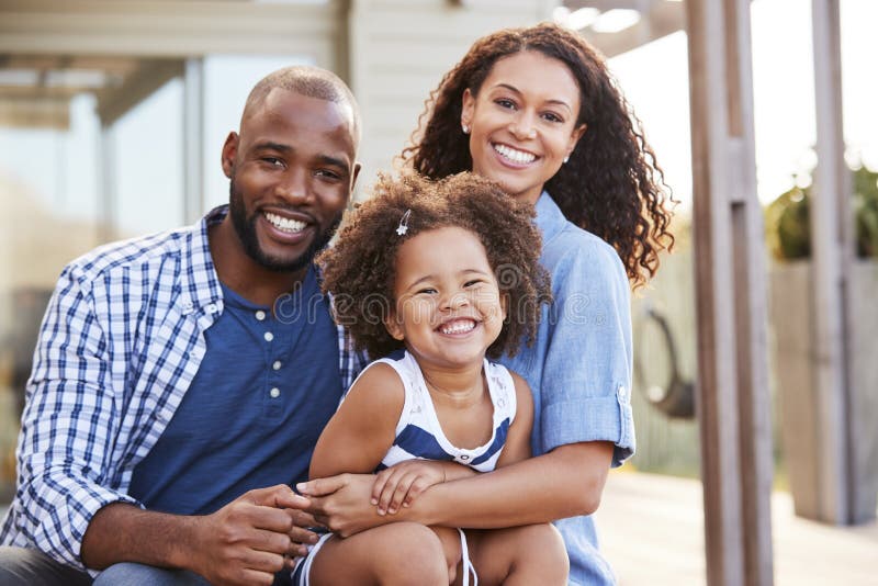 Young black family embracing outdoors and smiling at camera. Young black family embracing outdoors and smiling at camera