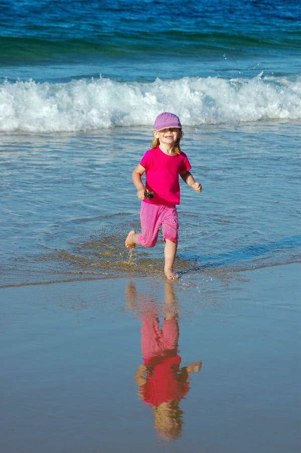 Little happy blond caucasian girl child in pink clothes playing in the sea and running in the water on the beach having great holiday fun. Little happy blond caucasian girl child in pink clothes playing in the sea and running in the water on the beach having great holiday fun