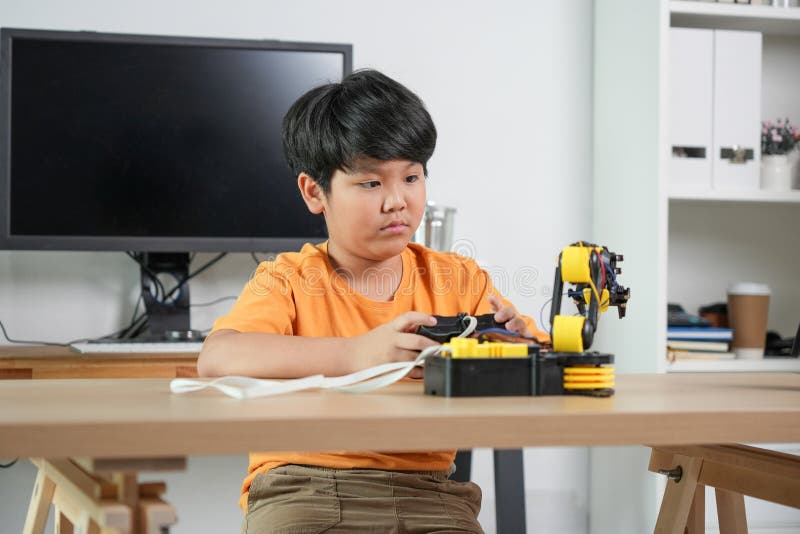 Barninlärningsrobotik och STEM-teknik Unga innovativa experiment med ingenjörskit Pojke Kontrollerar robotiskt arm på. Barninlärningsrobotik och STEM-teknik Unga innovatorexperiment med ingenjörskit Boy som kontrollerar robotisk arm hemma.