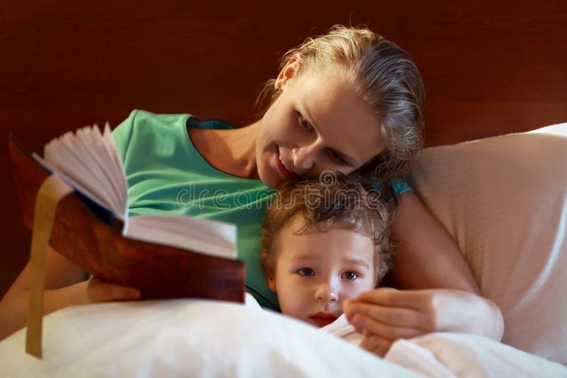 Barnmoder som läser till hennes barn i säng