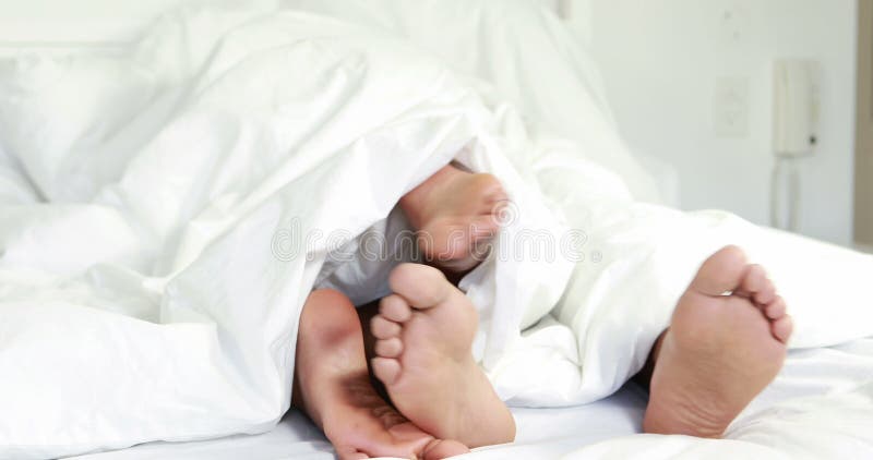 Barnpar under duntäcket i deras säng