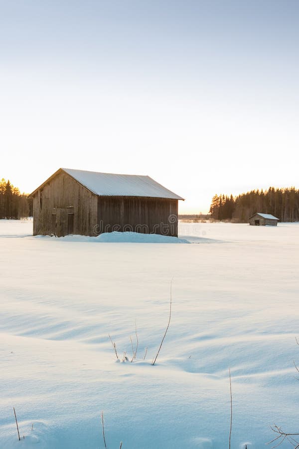 Barns In The Winter Sunrise 3. Two barns in a very cold morning against the late sunrise of the Finnish winter stock photo Barns In The Winter Sunrise 3. Two barns in a very cold morning against the late sunrise of the Finnish winter stock photo