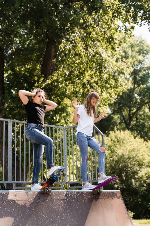 Barnvänlighet. Flickvänner som är redo att åka på penny-bord på skateboard-parklekplats. sportutrustning för royaltyfri fotografi
