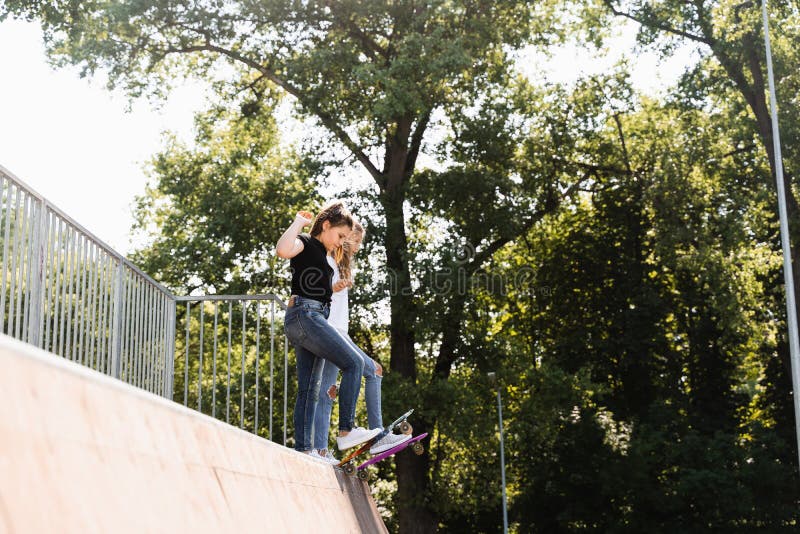 Barnvänlighet. Flickvänner som är redo att åka på penny-bord på skateboard-parklekplats. sportutrustning för royaltyfri fotografi