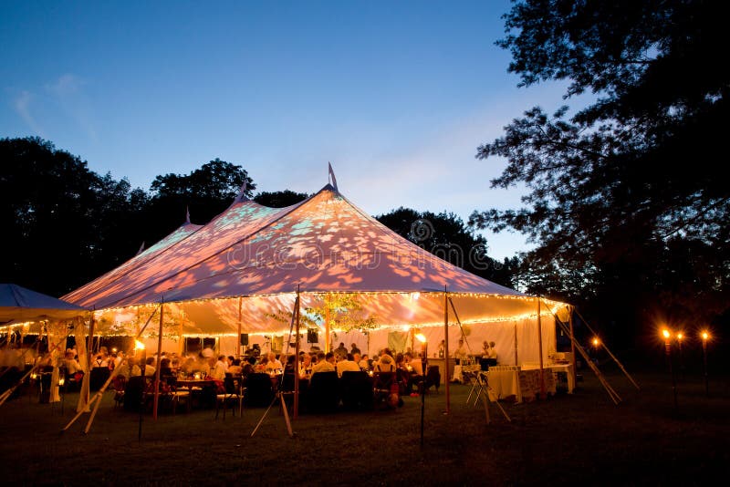Barraca do casamento na noite - a barraca do evento especial iluminou-se acima do interior com céu e árvores do crepúsculo