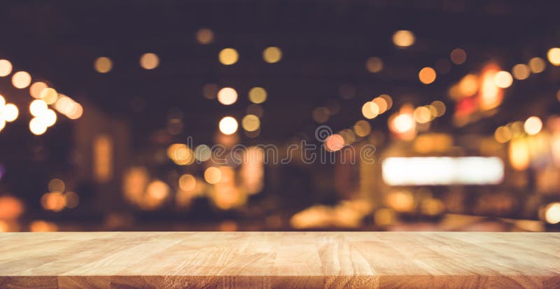 Barre en bois de dessus de table avec le bokeh de lumière de tache floue en café foncé de nuit