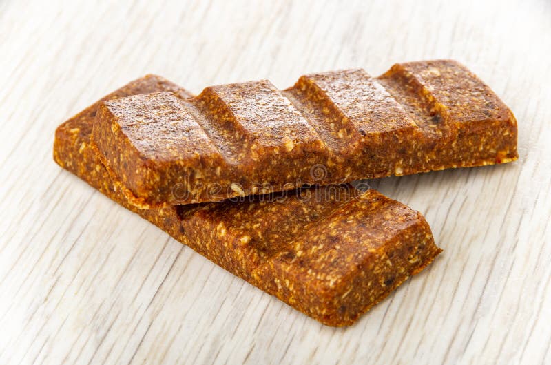 Barres d'énergie avec dattes et coco sur table. Deux barres énergétiques avec dattes et noix de coco sur une table en bois
