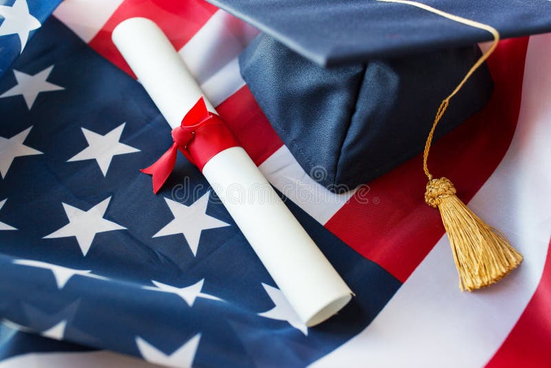 Education, graduation, patriotism and nationalism concept - close up of bachelor hat and diploma on american flag. Education, graduation, patriotism and nationalism concept - close up of bachelor hat and diploma on american flag