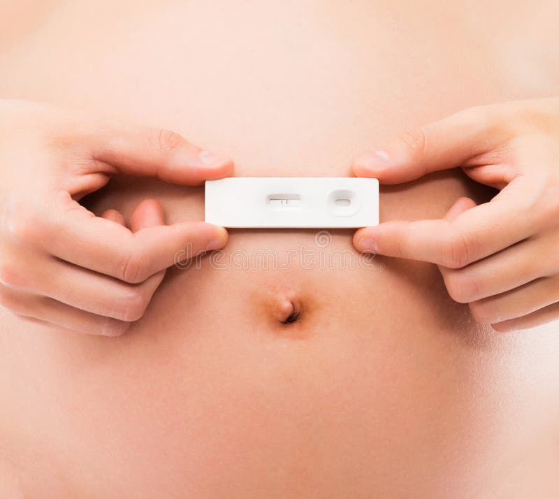 Barriga de uma mulher gravida que guarda um teste de gravidez foto de stock royalty free Barriga de uma mulher gravida que guarda um teste de gravidez foto de stock royalty free