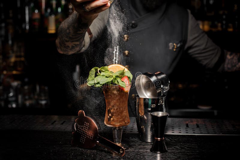 Bartender adding powder to a fresh summer cocktail with fruits