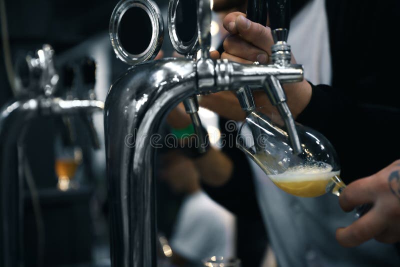Bartender pouring beer into glass in pub stock photo Bartender pouring beer into glass in pub stock photo