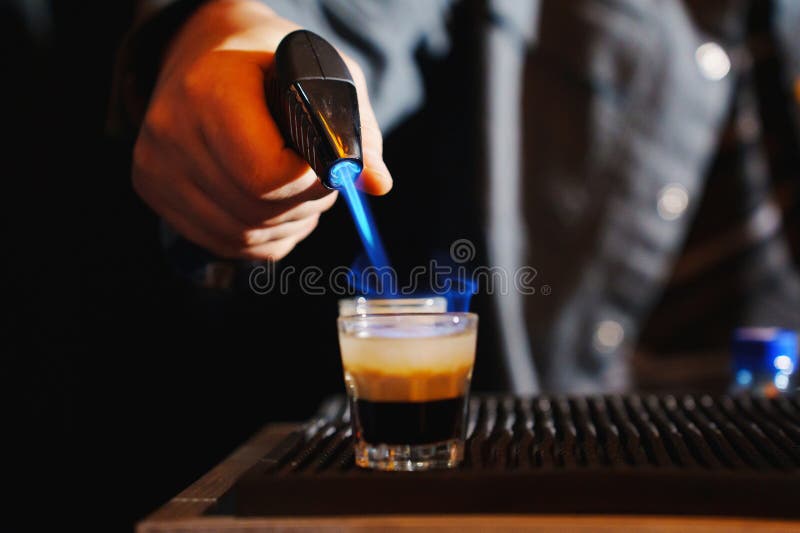 Bartender prepares a flaming cocktail using a handheld torch royalty free stock photos