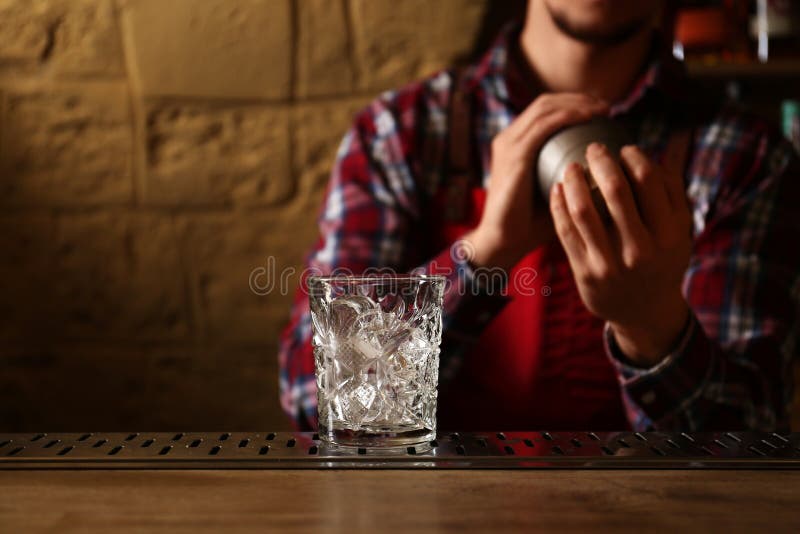 Bartender preparing alcoholic cocktail at bar counter, focus on glass stock photo Bartender preparing alcoholic cocktail at bar counter, focus on glass stock photo