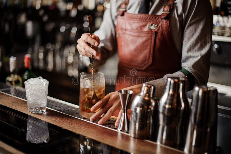 Bartender που δροσίζει έξω το γυαλί κοκτέιλ που αναμιγνύει τον πάγο με ένα κουτάλι στοκ φωτογραφία με δικαίωμα ελεύθερης χρήσης Bartender που δροσίζει έξω το γυαλί κοκτέιλ που αναμιγνύει τον πάγο με ένα κουτάλι στοκ φωτογραφία με δικαίωμα ελεύθερης χρήσης