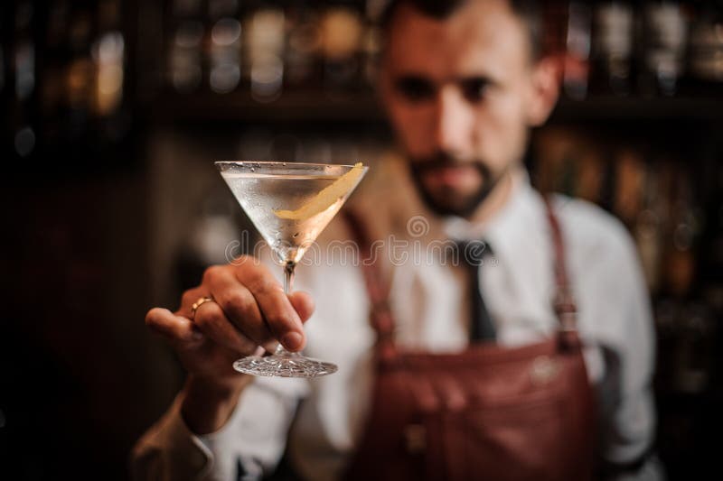 Bartender που κρατά ένα διαφανές κοκτέιλ στο martini γυαλί στοκ εικόνα Bartender που κρατά ένα διαφανές κοκτέιλ στο martini γυαλί στοκ εικόνα
