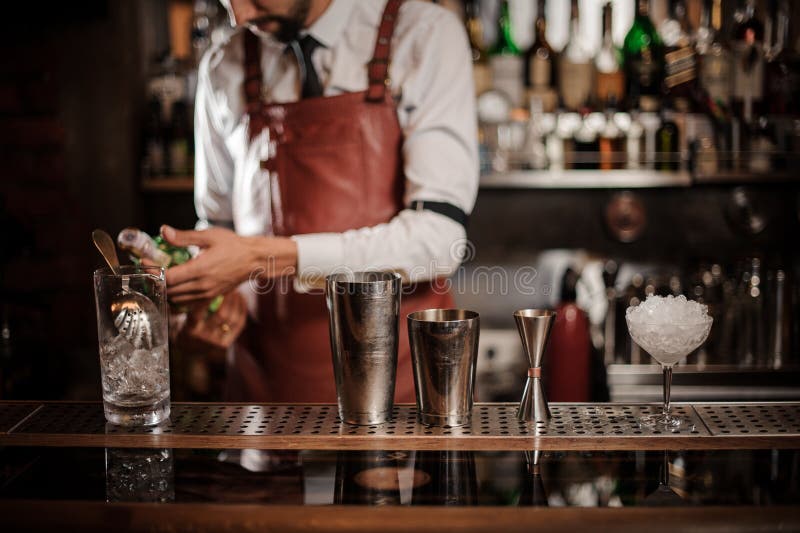 Bartender που κρατά ένα μπουκάλι του οινοπνευματώδους ποτού στο μετρητή φραγμών στοκ εικόνες Bartender που κρατά ένα μπουκάλι του οινοπνευματώδους ποτού στο μετρητή φραγμών στοκ εικόνες