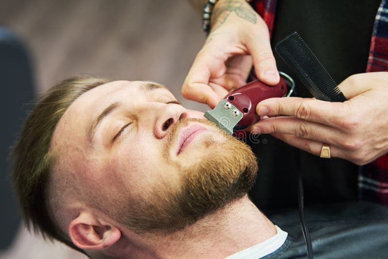 Bartsorgfalt Mann, während die Zutaten seines Gesichtshaares am Friseursalon schnitt