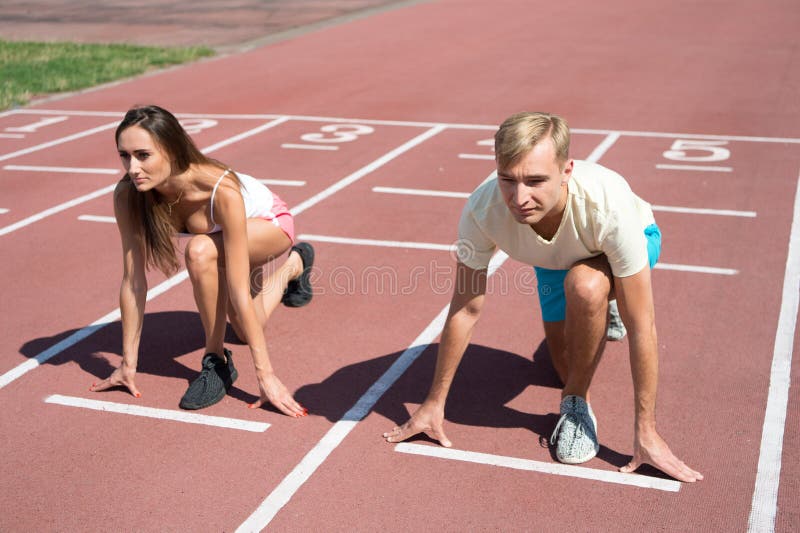 Man and women low start position running surface stadium. Running competition or gender race. Faster sportsman achieve victory. Sport challenge for couples. Everyone has chance. Equal forces concept. Man and women low start position running surface stadium. Running competition or gender race. Faster sportsman achieve victory. Sport challenge for couples. Everyone has chance. Equal forces concept.