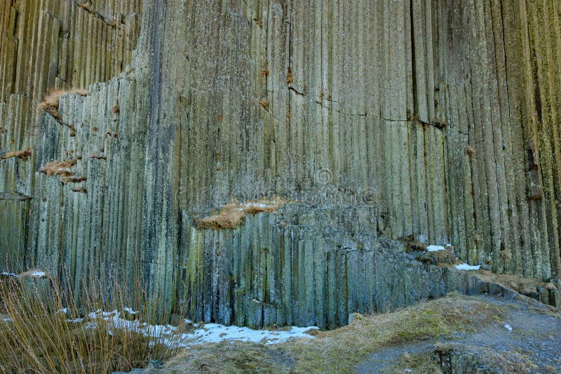 Basalt columns natural rock formation with vertical patterns and snow patches royalty free stock image
