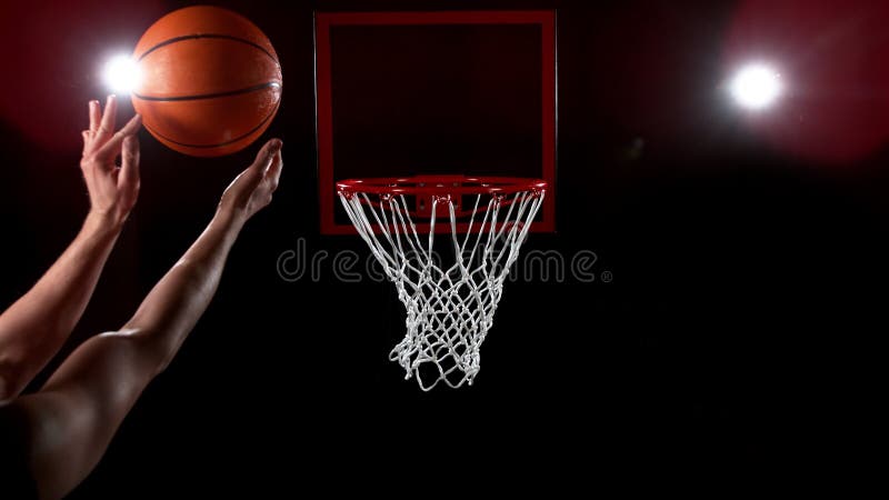 Baschet care trece prin coș pe fundal negru stock photography