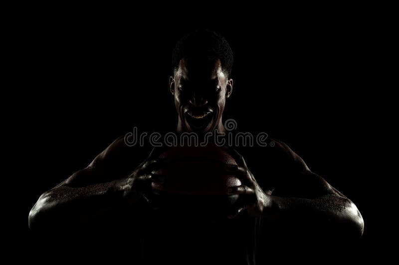 Baschetbalistul ținând mingea pe fundal negru. Femeie afro-americană suferind țipând stock photography