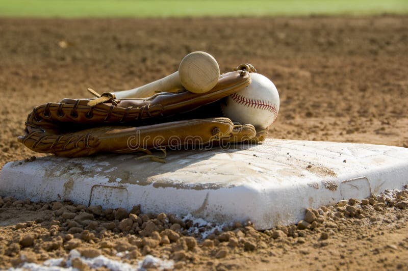 Baseball bat, glove and ball on 1st base at field. Baseball bat, glove and ball on 1st base at field